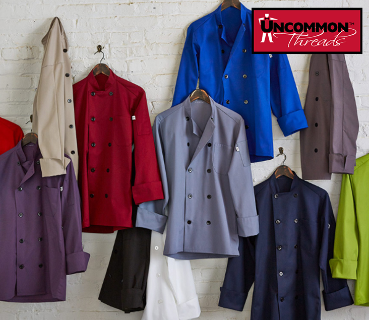 Chef clothing from Uncommon Threads hanging on a brick wall.